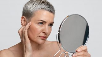 Skin Aging. Mature woman looking in the mirror checking her wrinkles